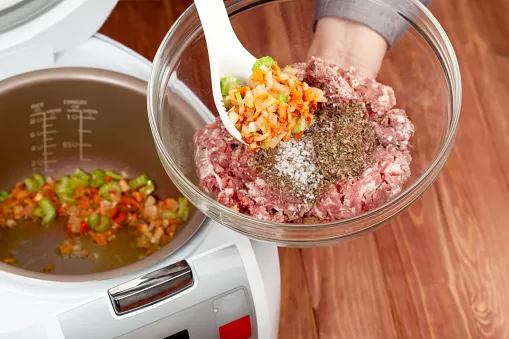 Cooking ground meat with roasted vegetables in multicooker closeup